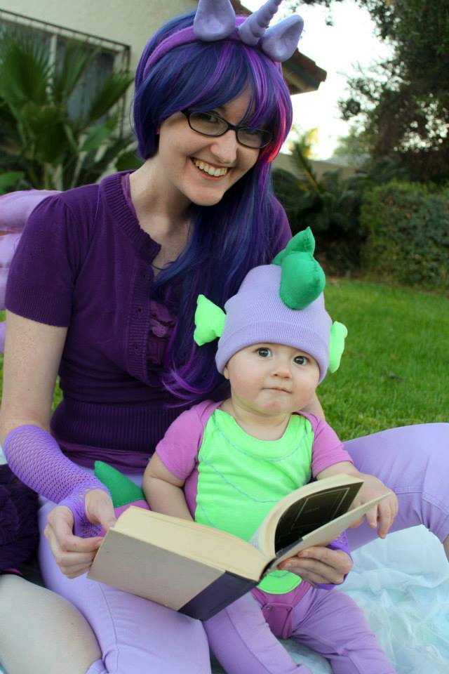 Laci Morgan cosplay as Twilight Sparkle, reading a book with a baby dressed in a Spike the Dragon costume