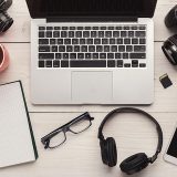 Top view on creative designer workplace with photo equipment, computer, headphones and blank notepad, freelance and remote work from home concept, copy space