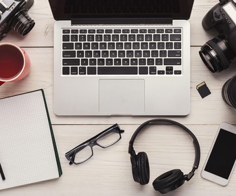 Top view on creative designer workplace with photo equipment, computer, headphones and blank notepad, freelance and remote work from home concept, copy space