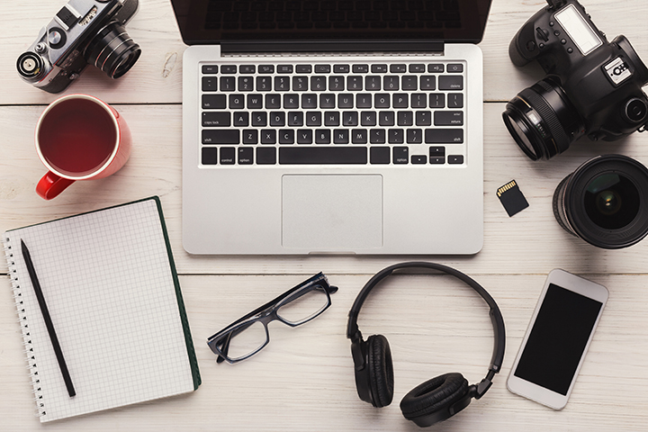 Top view on creative designer workplace with photo equipment, computer, headphones and blank notepad, freelance and remote work from home concept, copy space