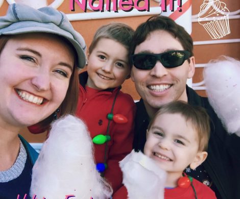 The Morgan family posing in front of a gingerbread house, eating cotton candy