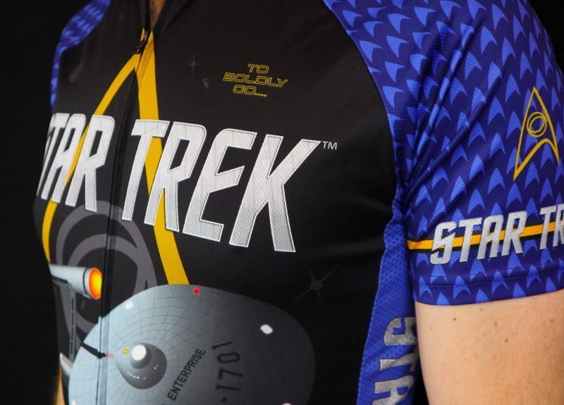 Closeup of a blue Star Trek cycling jersey featuring the Enterprise and delta logo, part of the fitness apparel line from Brainstorm Gear