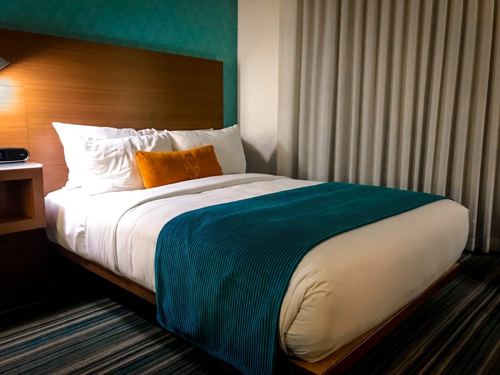 Double size bed with turquoise duvet cover and orange pillow at the Shore Hotel Santa Monica