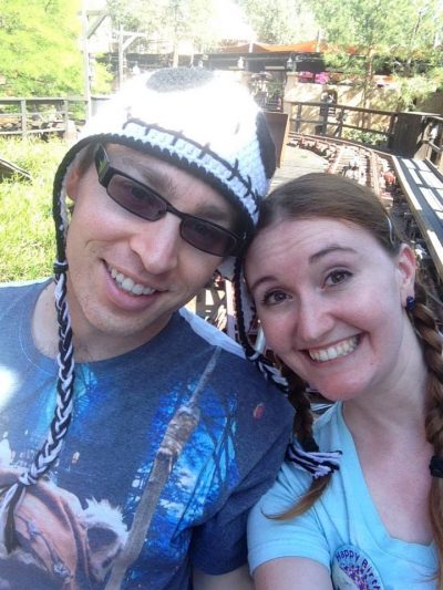 A smiling couple sitting in the back train car of Thunder Mountain Railroad at Disneyland.