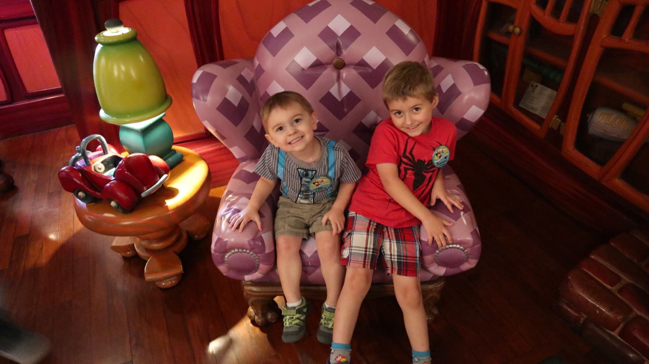 two smiling little boys sitting in a purple chair in Mickey's House in Toontown at Disneyland