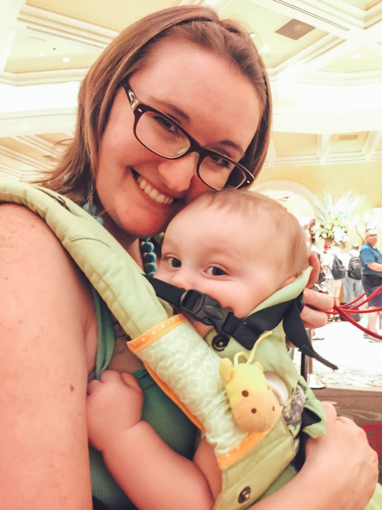 A happy baby and mom wearing a green Lillebaby Organic Complete baby carrier