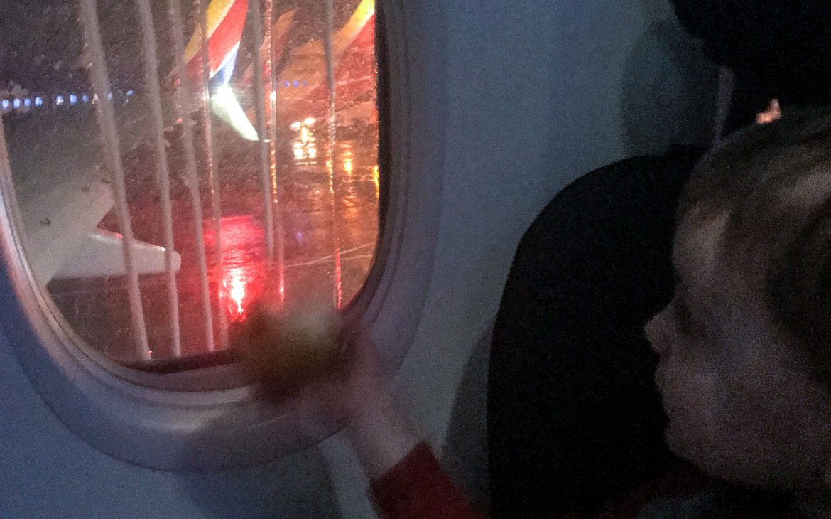 A boy watches out the plane window as the airplane is de-iced