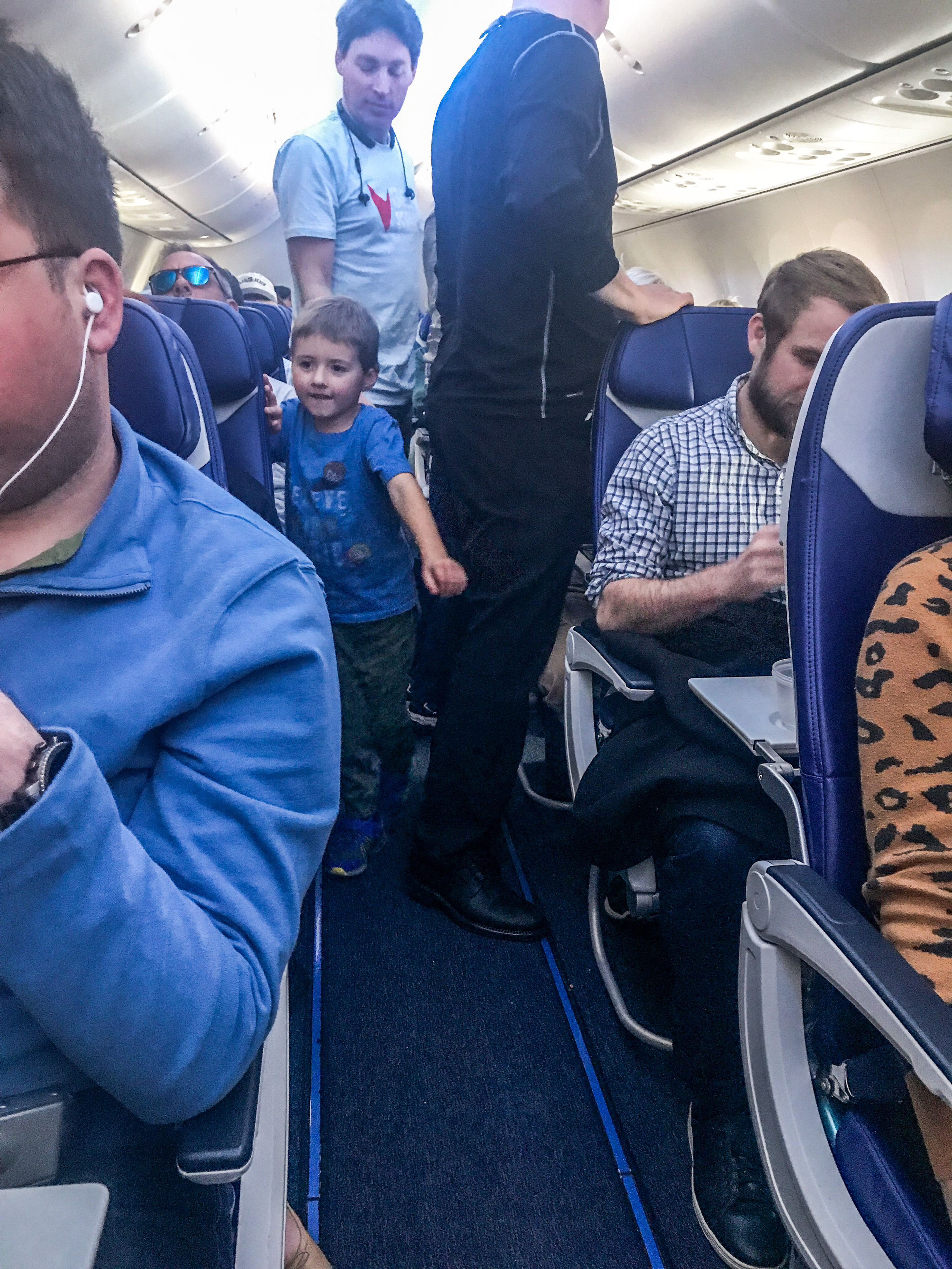 A little boy walking down an airplane aisle