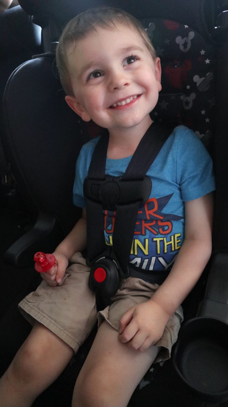 A little boy smiling in his car seat