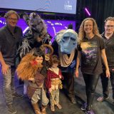 The Morgan family in the Dark Crystal: Age of Resistance cosplay as a Skeksis, Mystic, Rian and Hup, pictured with the Jim Henson Studios team